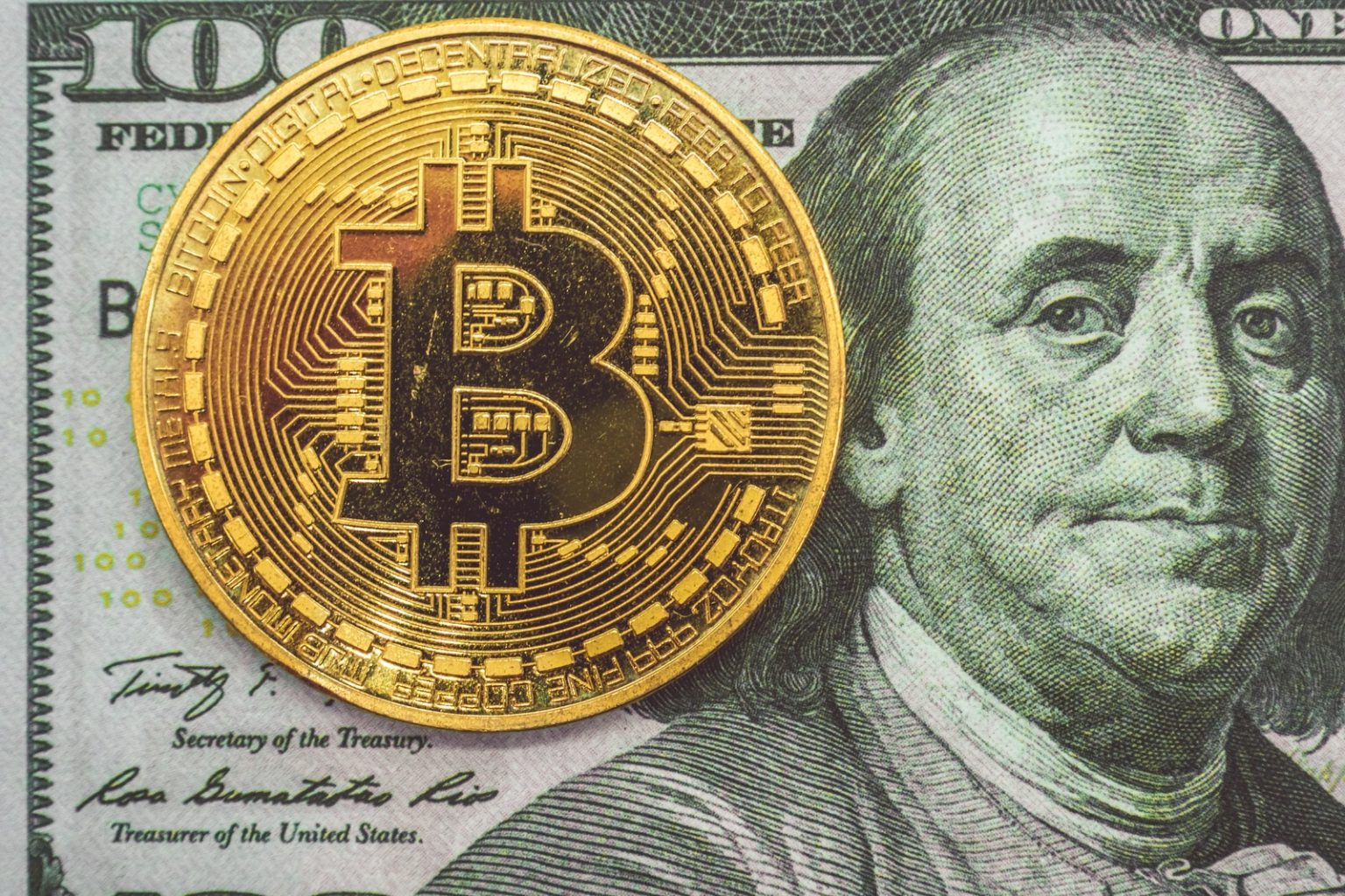 Moeda de Bitcoin em cima de nota de dólar (Bermix Studio)