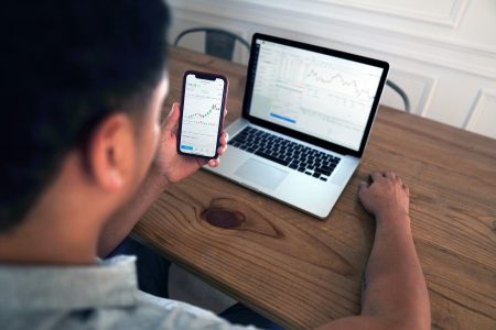 Homem segurando celular e olhando notebook (MayoFi)