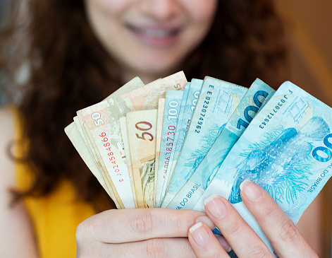 Mulher com notas de R$ 100 (Royalty Free))