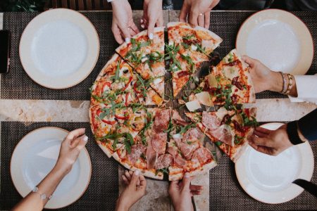 Pessoas pegando fatias de pizza (Klara Kulikova)