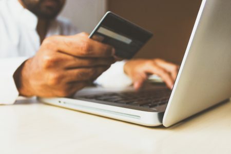 Homem segurando cartão de crédito no Notbook (Rupixen.com)