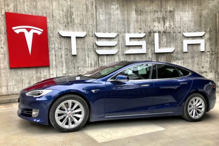 Sedan azul estacionado embaixo do letreiro da Testa (Tesla Fans Schweiz)