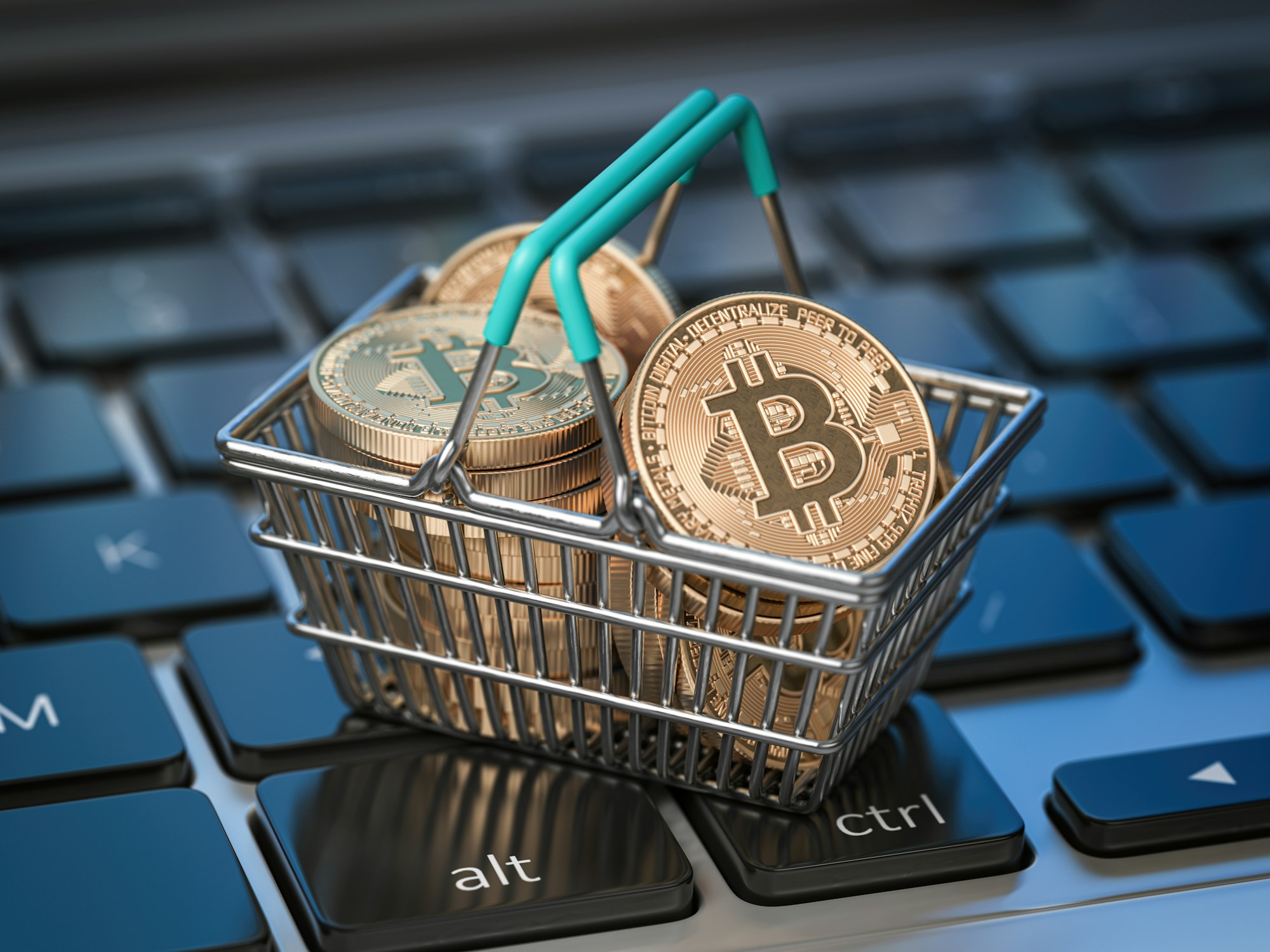 Bitcoin coins in shopping basket on laptop keyboard. Bitcoin wallet and payment.
